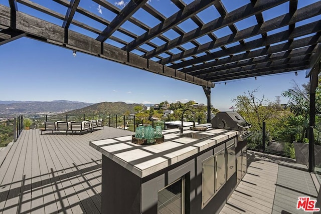 wooden terrace with area for grilling, grilling area, a pergola, and a mountain view