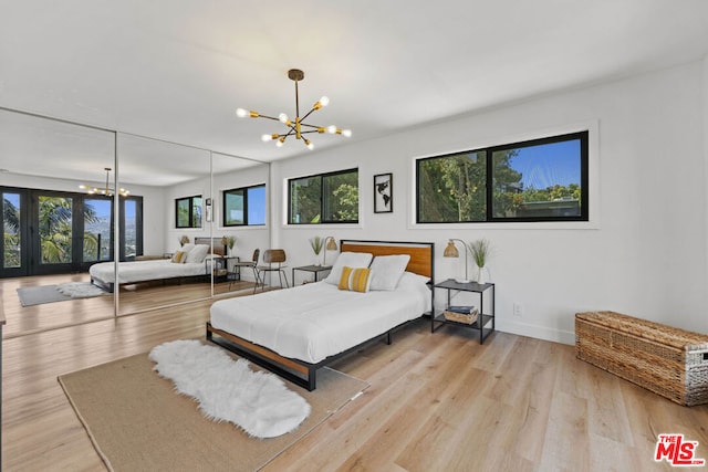 bedroom with multiple windows, an inviting chandelier, and light hardwood / wood-style floors