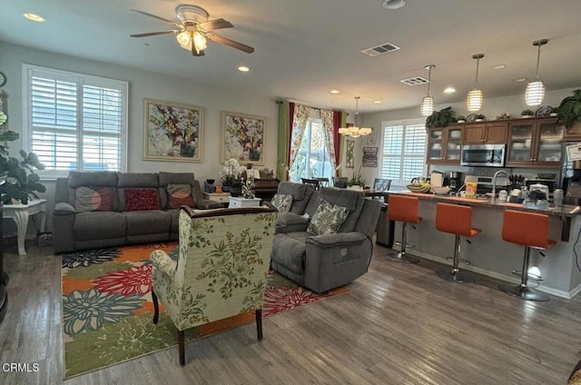 living room featuring dark hardwood / wood-style flooring, ceiling fan with notable chandelier, and a wealth of natural light