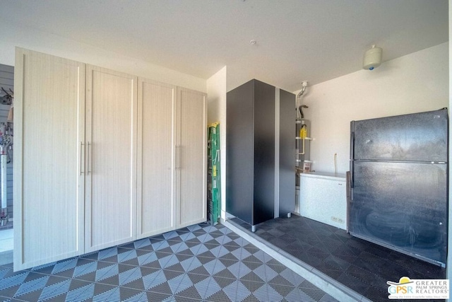 kitchen featuring black refrigerator, light brown cabinets, and water heater