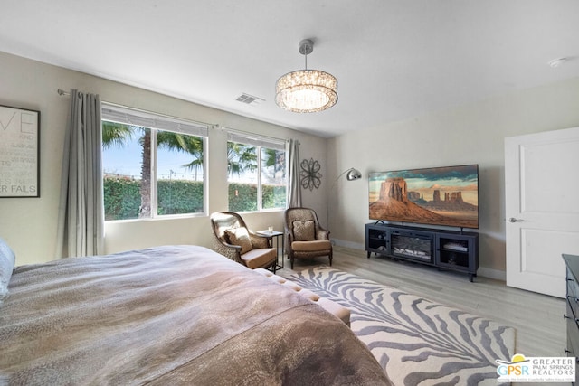 bedroom with light hardwood / wood-style flooring and a chandelier