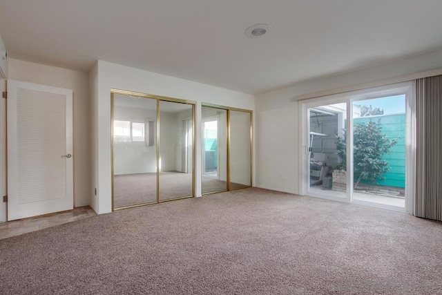 unfurnished bedroom with carpet floors, access to outside, and multiple closets