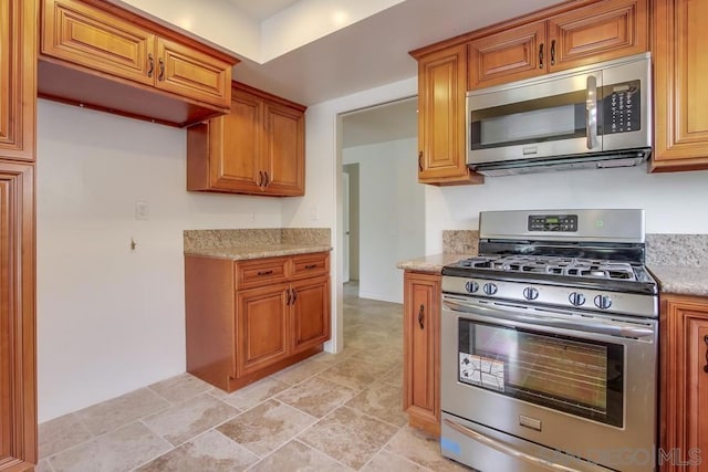 kitchen with appliances with stainless steel finishes and light stone counters