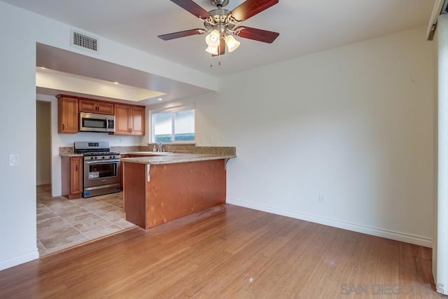 kitchen featuring kitchen peninsula, sink, light hardwood / wood-style floors, and appliances with stainless steel finishes