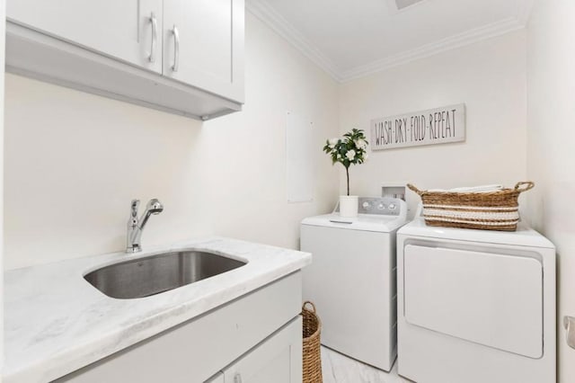 washroom featuring cabinets, ornamental molding, washing machine and clothes dryer, and sink