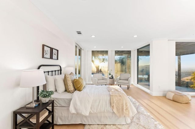 bedroom with hardwood / wood-style flooring and a wall of windows