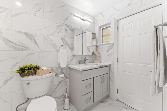 bathroom with toilet, vanity, and tile walls