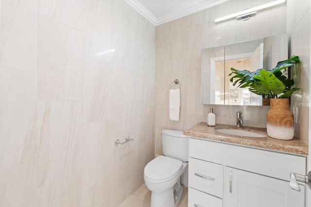 bathroom featuring tile walls, toilet, vanity, and ornamental molding