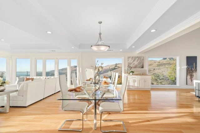 dining area featuring light wood-type flooring, a wealth of natural light, a tray ceiling, and ornamental molding