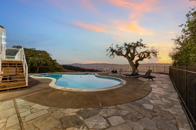 pool at dusk featuring a mountain view and a patio