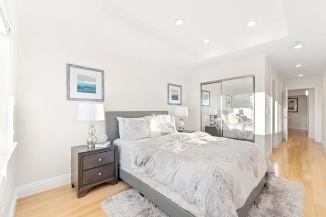 bedroom featuring a closet, a tray ceiling, and light hardwood / wood-style floors