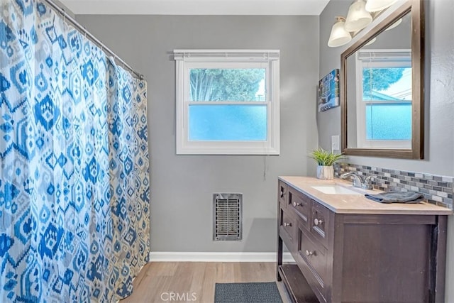13621 Arcturus Ave, Gardena, CA 90249 - bathroom featuring wood finished floors, vanity, decorative backsplash, and healthy amount of natural light