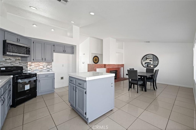 kitchen featuring a center island, black stove, vaulted ceiling, decorative backsplash, and light tile patterned floors