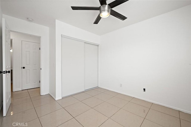 unfurnished bedroom featuring ceiling fan, light tile patterned floors, and a closet