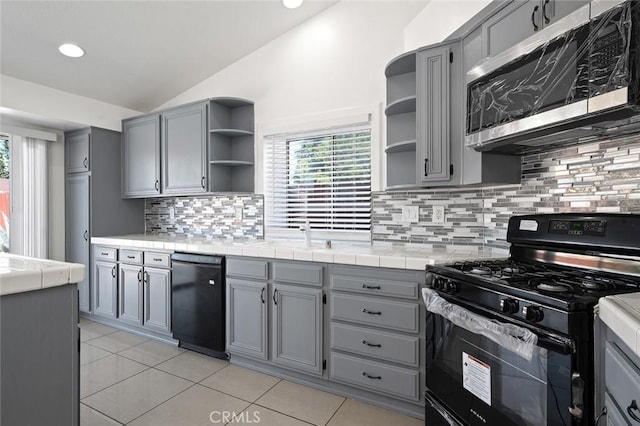 kitchen featuring plenty of natural light, tile counters, lofted ceiling, and black appliances