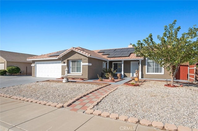 ranch-style home featuring a garage and solar panels