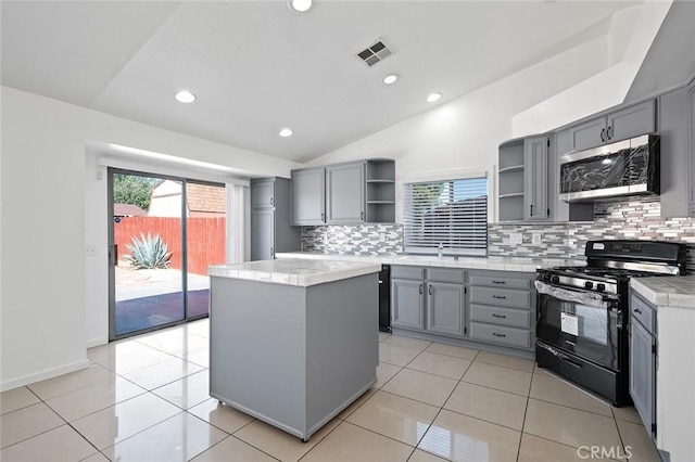 kitchen featuring tasteful backsplash, light tile patterned floors, black gas range, a kitchen island, and lofted ceiling