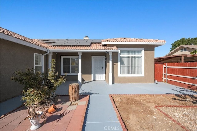 view of front of home featuring solar panels and a patio