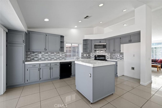 kitchen featuring decorative backsplash, black appliances, a kitchen island, tile counters, and lofted ceiling