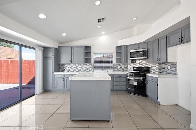 kitchen featuring lofted ceiling, gas stove, light tile patterned floors, and tasteful backsplash