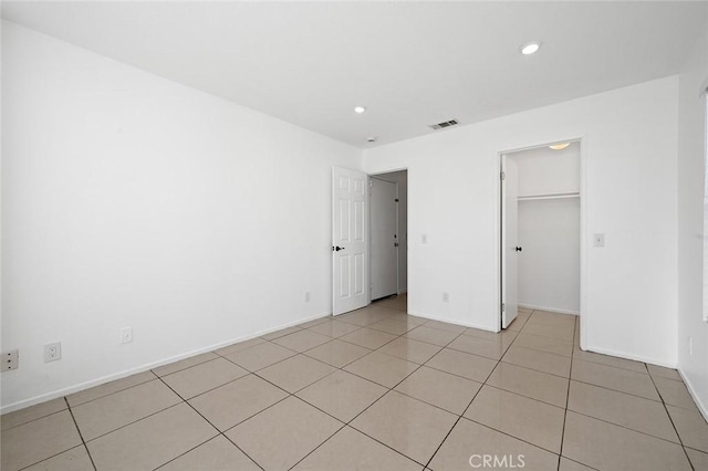 unfurnished bedroom featuring a spacious closet, a closet, and light tile patterned floors