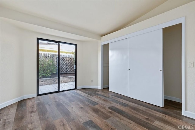 unfurnished bedroom featuring access to exterior, dark hardwood / wood-style floors, a closet, and vaulted ceiling