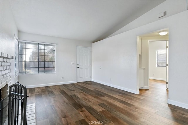 spare room featuring vaulted ceiling, a fireplace, and dark hardwood / wood-style floors