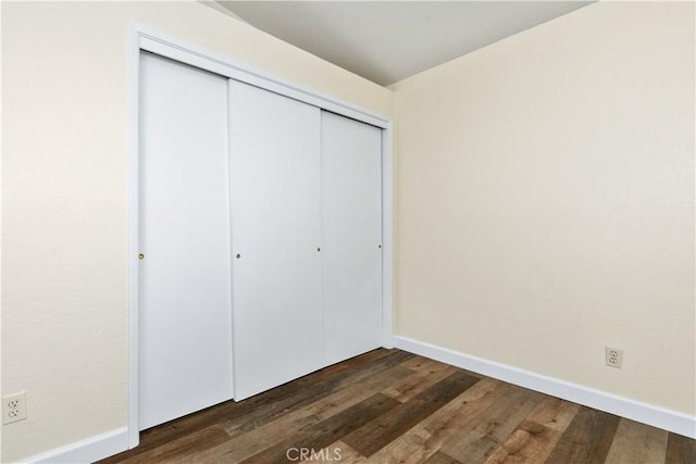 unfurnished bedroom featuring dark wood-type flooring and a closet