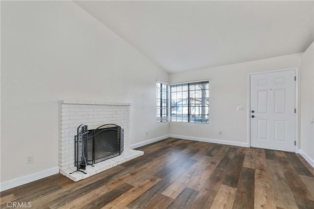 unfurnished living room with vaulted ceiling, a brick fireplace, and dark hardwood / wood-style flooring