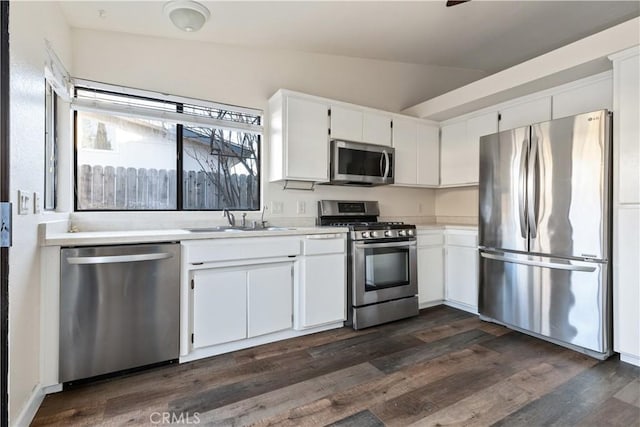 kitchen featuring white cabinets, appliances with stainless steel finishes, sink, and vaulted ceiling