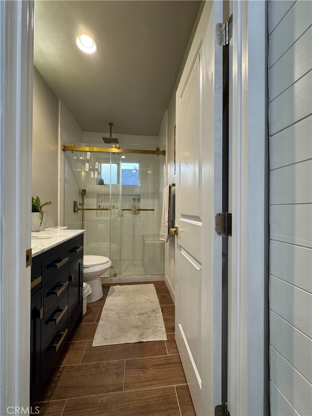 bathroom with toilet, a shower with door, and vanity