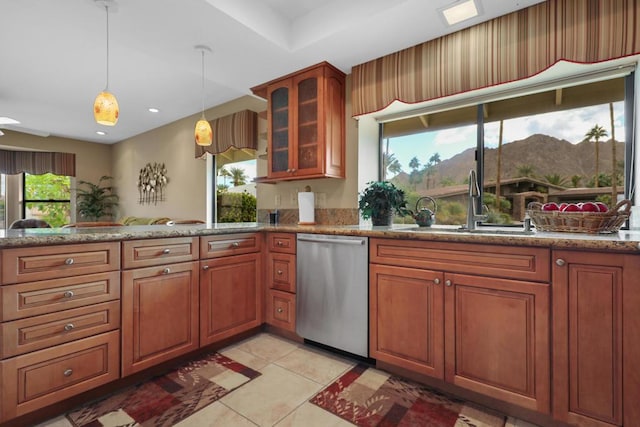 kitchen with light stone countertops, dishwasher, sink, a mountain view, and light tile patterned floors