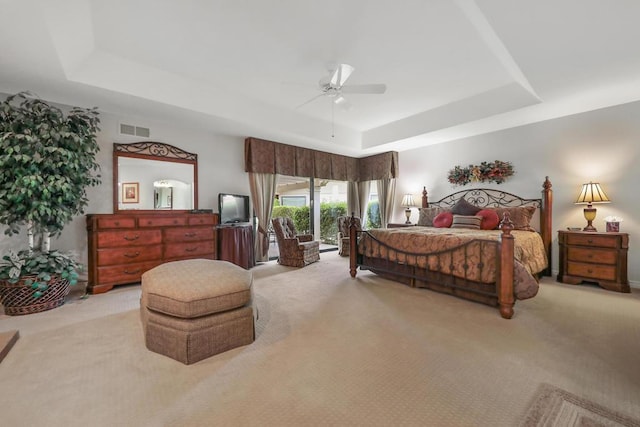 carpeted bedroom featuring ceiling fan, access to outside, and a tray ceiling