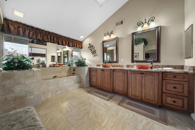 bathroom with tiled bath, vanity, and high vaulted ceiling