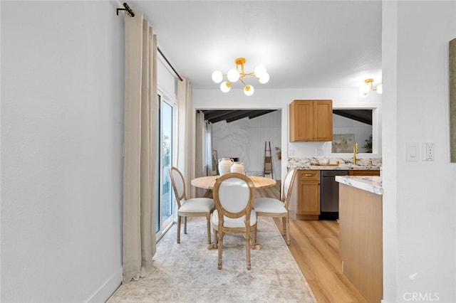 dining room with a wealth of natural light, sink, an inviting chandelier, and light wood-type flooring