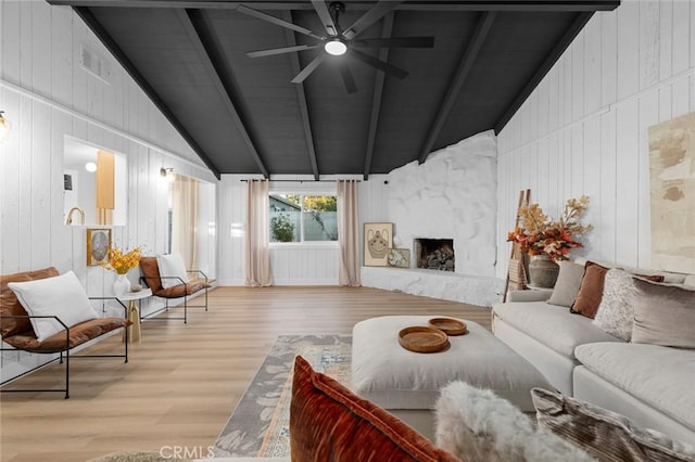 living room featuring a fireplace, vaulted ceiling with beams, light hardwood / wood-style floors, and wooden walls