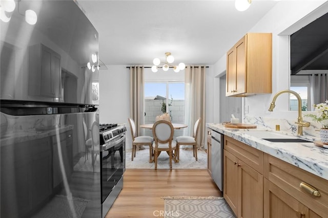 kitchen with sink, light hardwood / wood-style flooring, light stone countertops, a notable chandelier, and stainless steel appliances