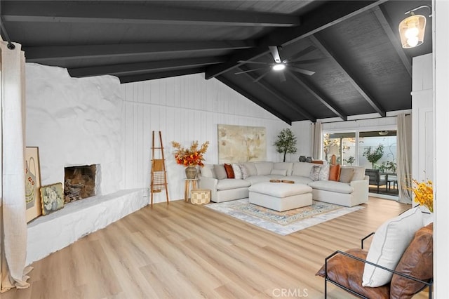 living room featuring wood-type flooring, vaulted ceiling with beams, a stone fireplace, and ceiling fan