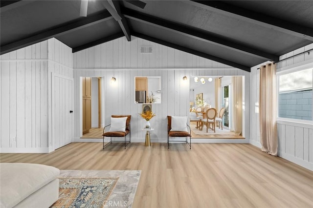 sitting room with vaulted ceiling with beams, wood walls, and light hardwood / wood-style flooring