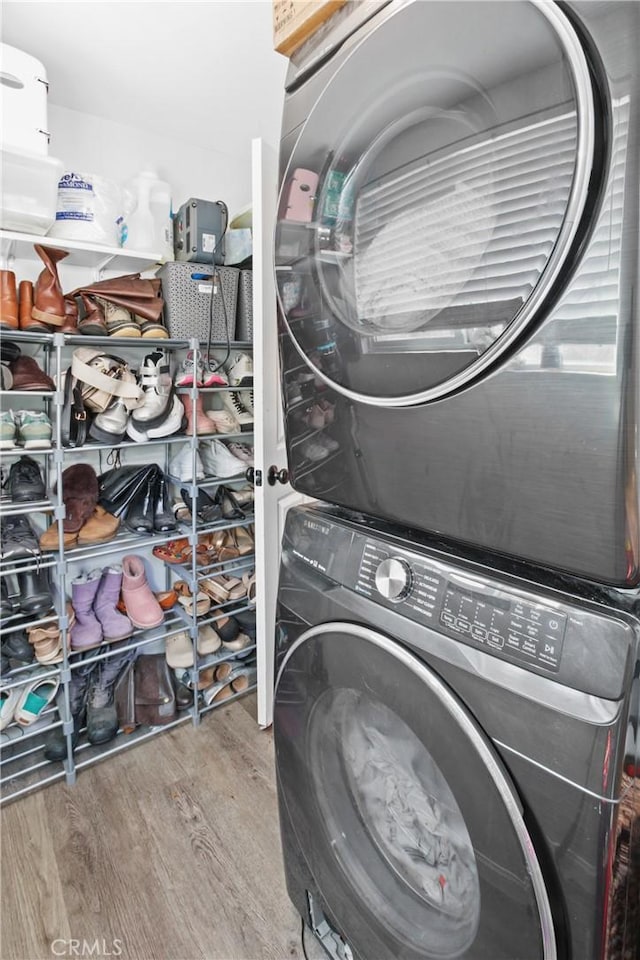 laundry area with hardwood / wood-style floors and stacked washer and dryer