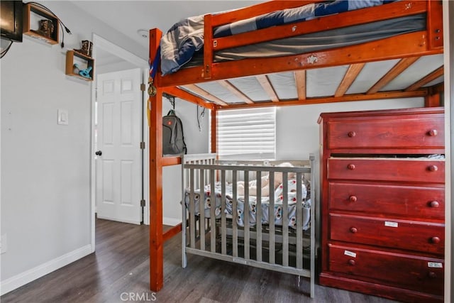 bedroom with a nursery area and dark wood-type flooring