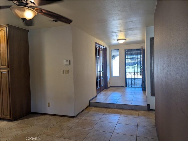 tiled entrance foyer featuring ceiling fan and a textured ceiling