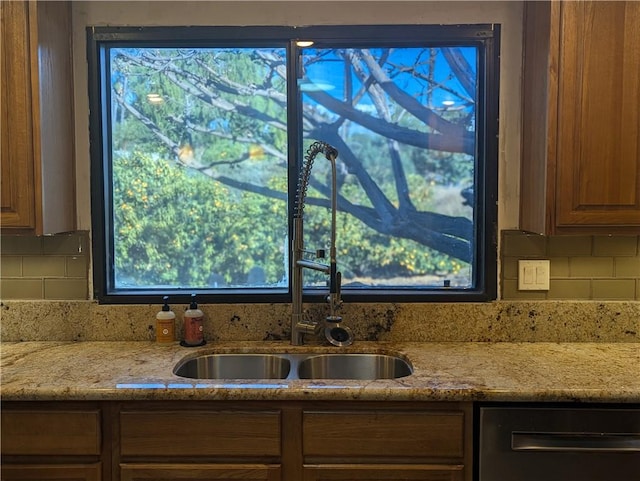 kitchen with tasteful backsplash, light stone countertops, dishwasher, and sink