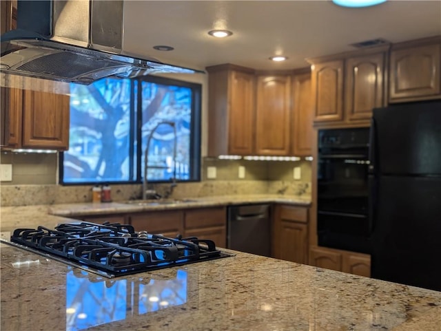 kitchen with ventilation hood, light stone countertops, black appliances, and sink