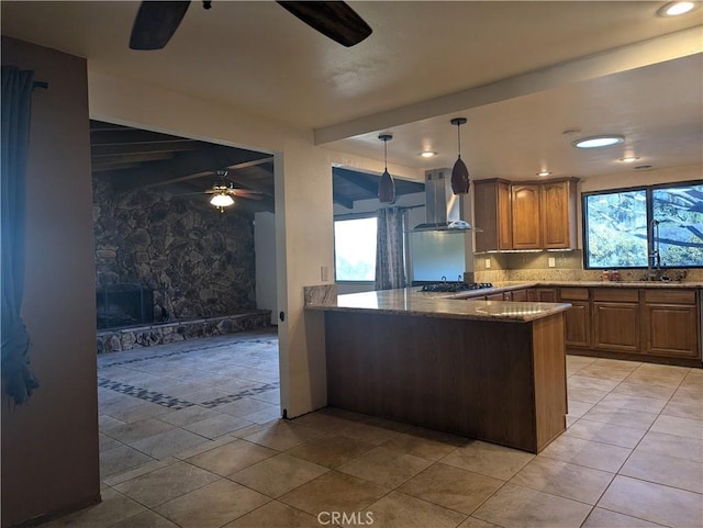 kitchen with sink, hanging light fixtures, kitchen peninsula, stainless steel gas cooktop, and range hood