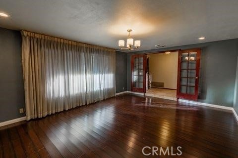 empty room featuring french doors, hardwood / wood-style flooring, and a notable chandelier