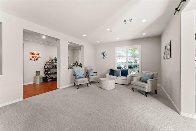 sitting room with a barn door and light colored carpet