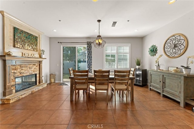 tiled dining space featuring a stone fireplace and a chandelier