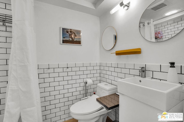 bathroom with tile walls, toilet, vanity, and a shower with shower curtain