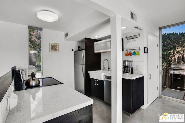 kitchen featuring stainless steel appliances, a wall of windows, plenty of natural light, and sink